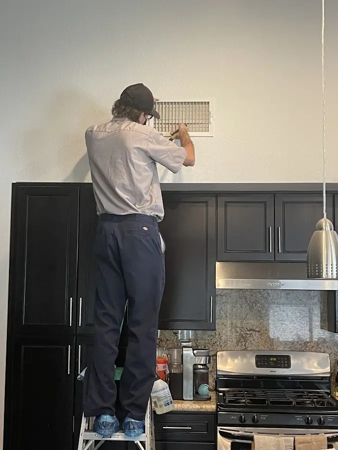 Technician inspecting an air vent during HVAC service in Avon